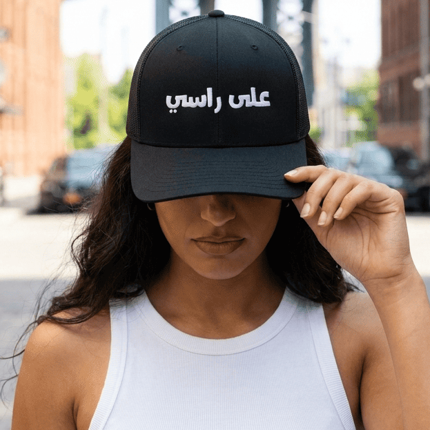 Model wearing 3ala Rasi embroidered trucker cap, side angle, Arabic slogan headwear by BOSA