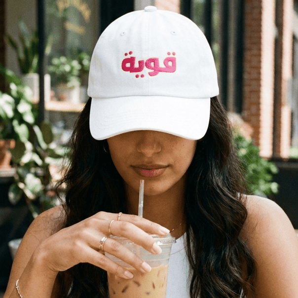Model wearing Qawiyah Arabic script dad hat, Arabic strong woman slogan cap by BOSA